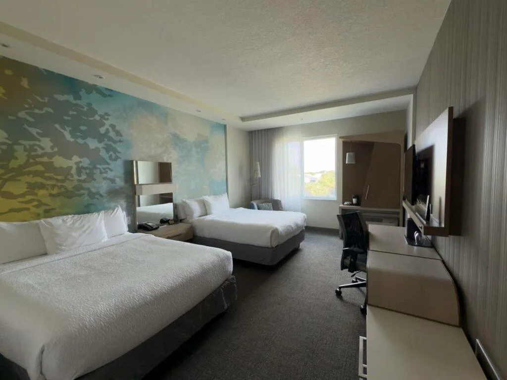 Standard two-queen room with beds, desk, and TV