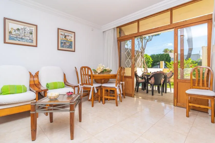 A bright living and dining area opens onto a patio with outdoor seating.