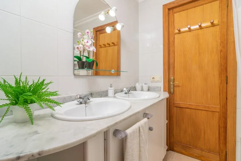 A bathroom vanity with two sinks, a mirror, and a wooden door.