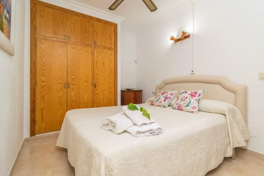 A bedroom with a neatly made bed and wooden built-in closets.