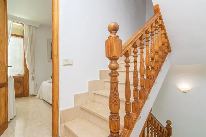 A staircase with wooden railings rises beside a doorway to a bedroom.