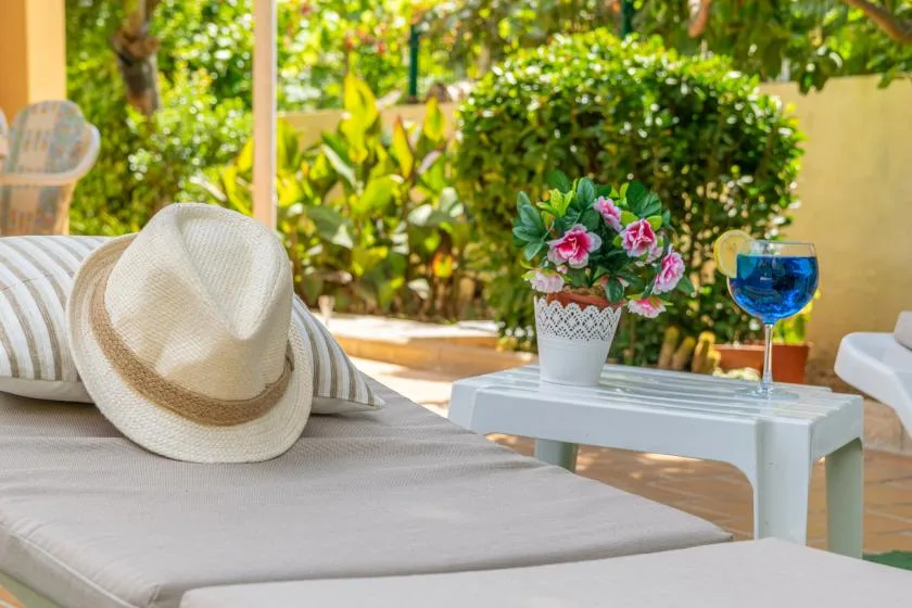 A shaded outdoor seating area with a sunhat and potted flowers.