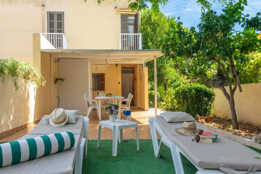 An outdoor patio with lounge seating, a table, and greenery.