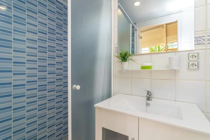 A bright bathroom with a white sink, mirror, and blue tiled wall.