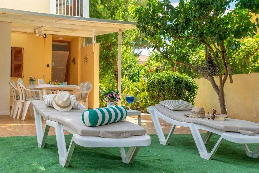 Outdoor patio with lounge seating beside a shaded garden.