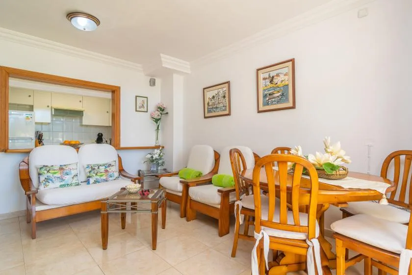 A dining area with wooden seating and a table beside an open kitchen.