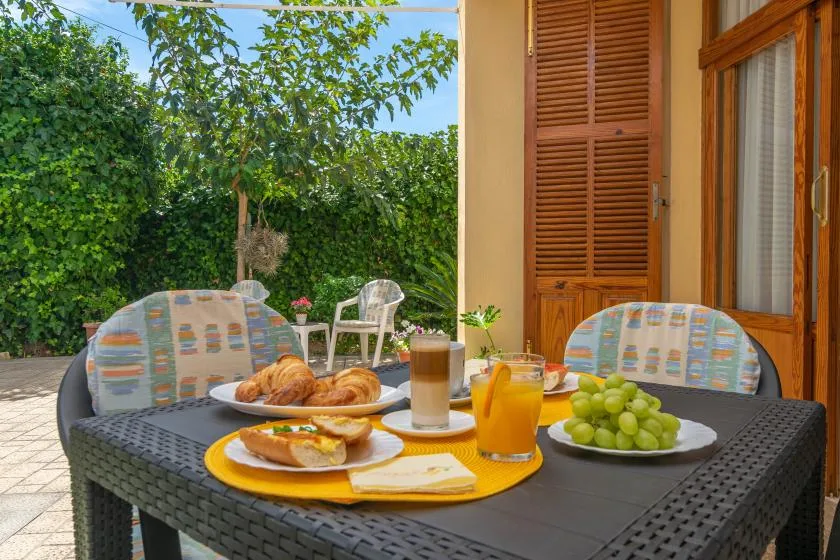 A patio table is set with breakfast, juice, coffee, and grapes.