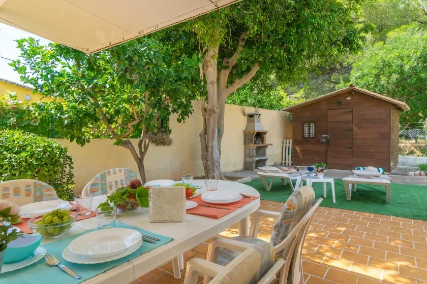 An outdoor dining area beneath leafy trees, with a table and seating.