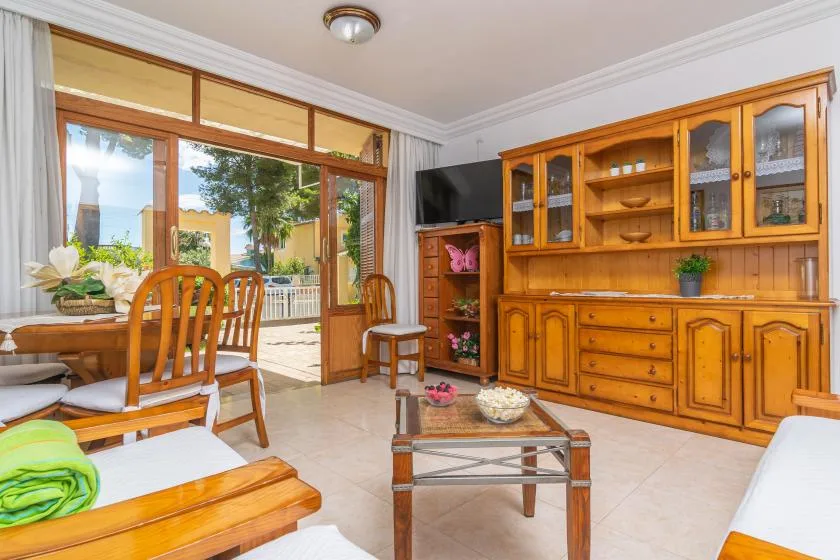 A living room with wooden seating, a glass coffee table, and a large display cabinet.