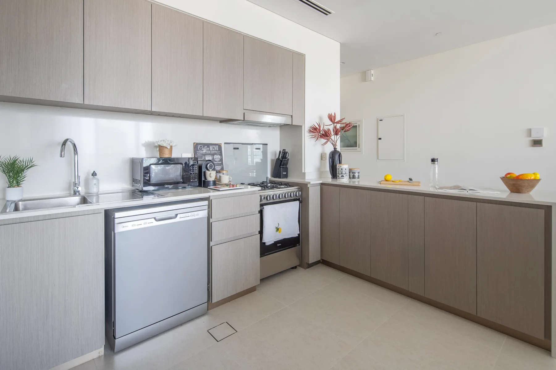 Una cocina moderna con muebles claros, una encimera y electrodomésticos integrados.