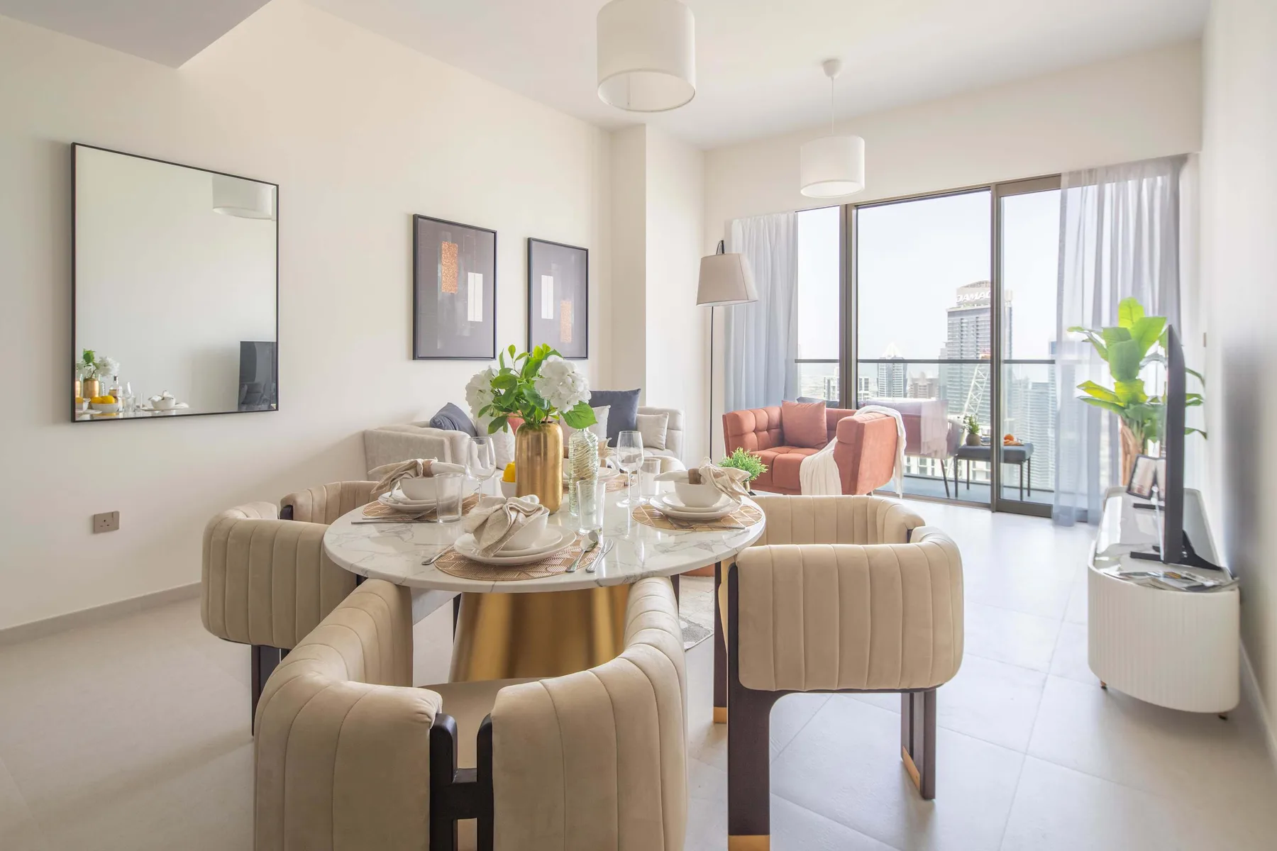 Una luminosa zona de comedor y estar con la mesa puesta junto a grandes ventanales.