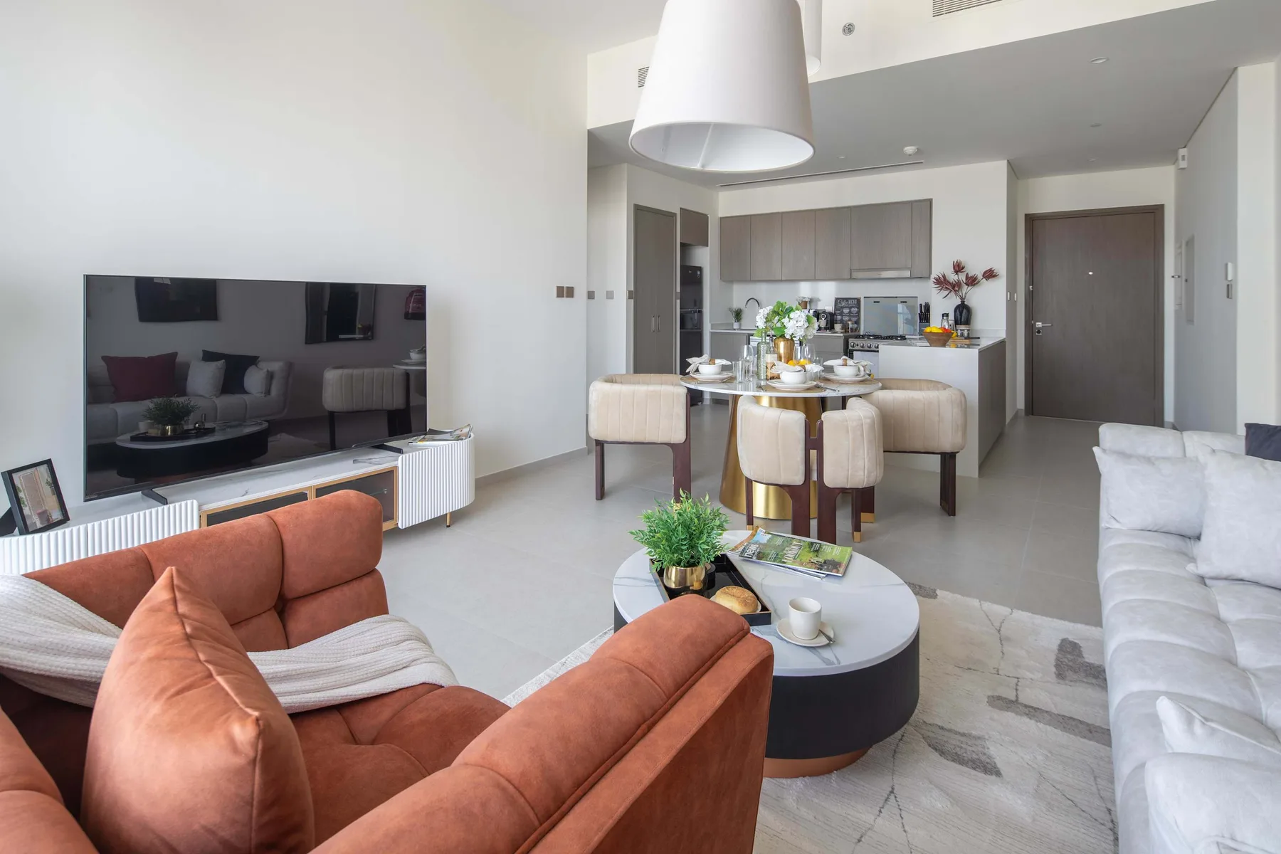 Una sala de estar se abre a una cocina, con asientos alrededor de una mesa de centro.