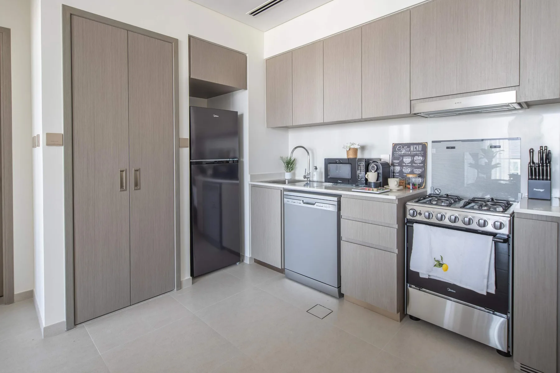 Una cocina moderna con gabinetes grises, un refrigerador y una estufa de acero inoxidable.