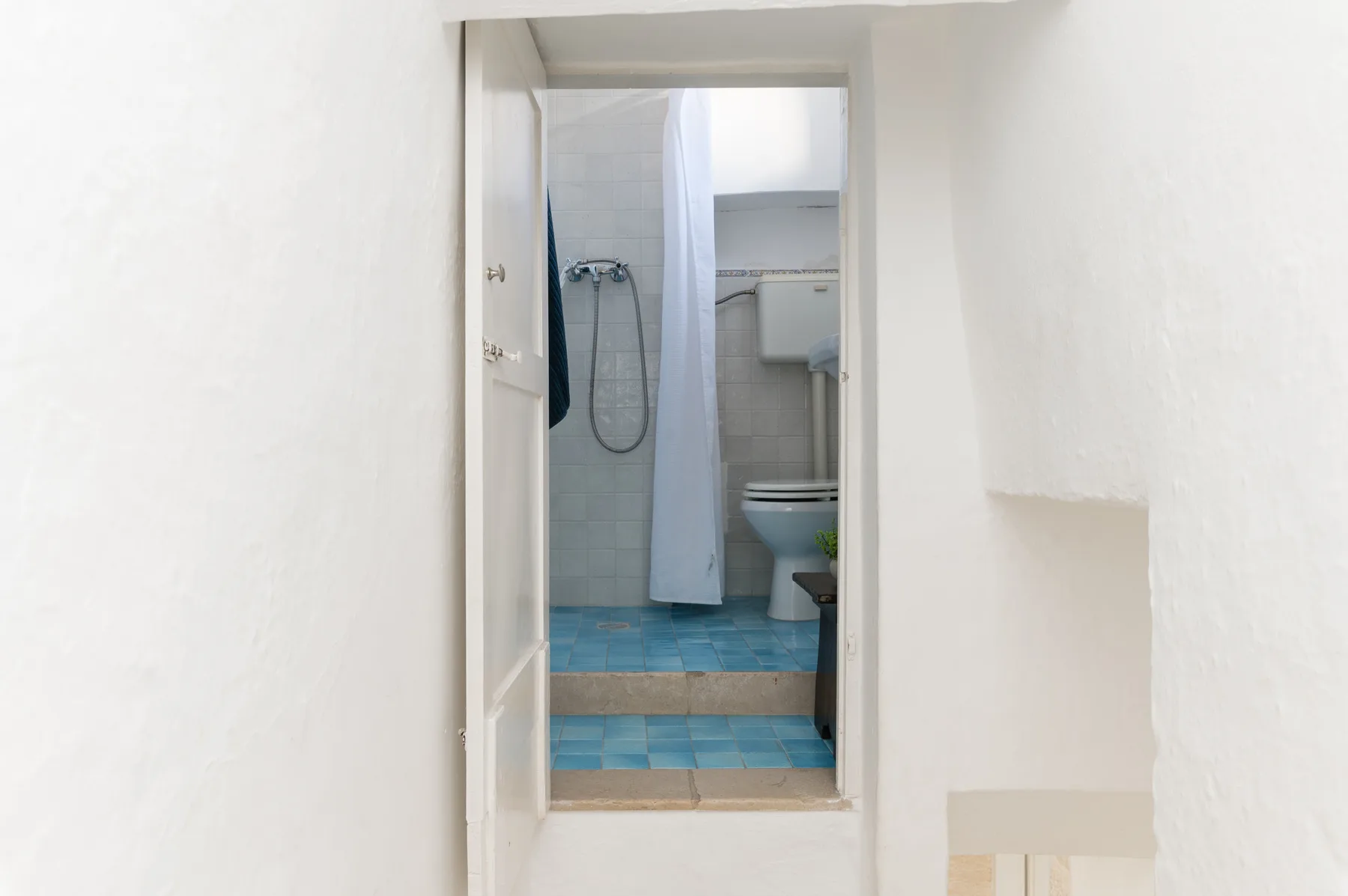 A bathroom is visible through an open doorway, with a shower and toilet.