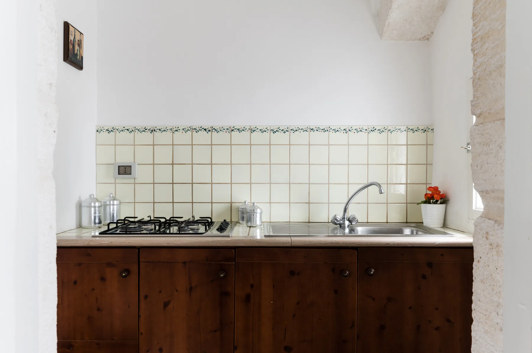 A kitchen counter with a gas cooktop, sink, and dark wooden cabinets.