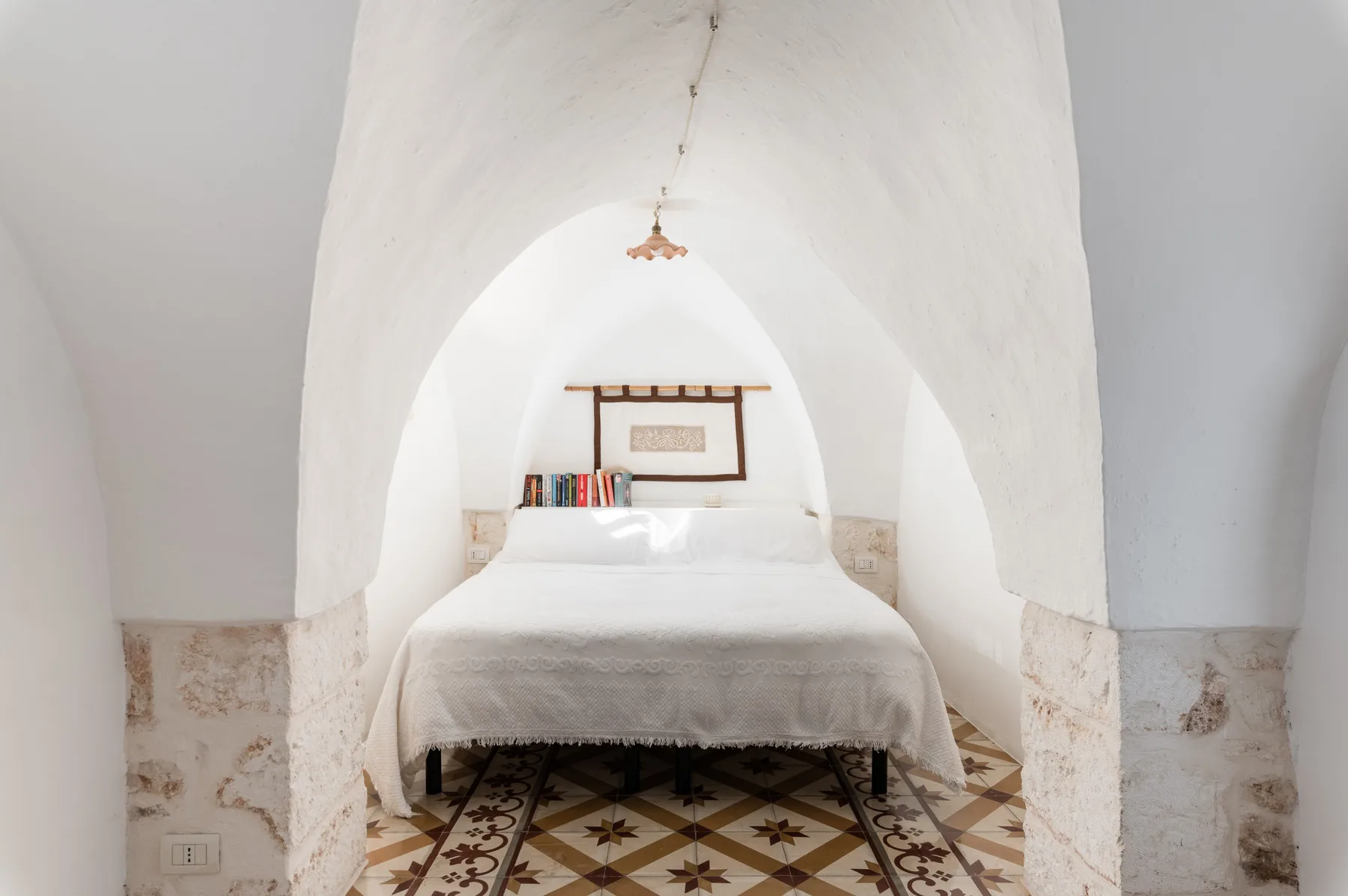 A bedroom with a bed beneath a white arched ceiling.