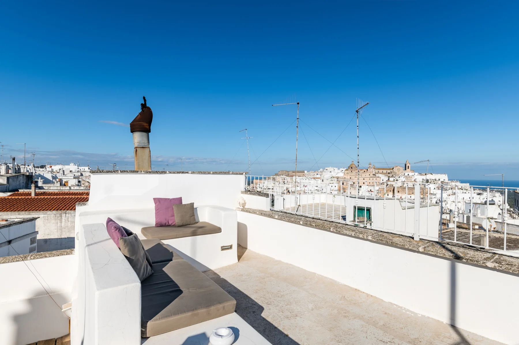 A rooftop terrace with built-in seating overlooks a dense whitewashed cityscape.