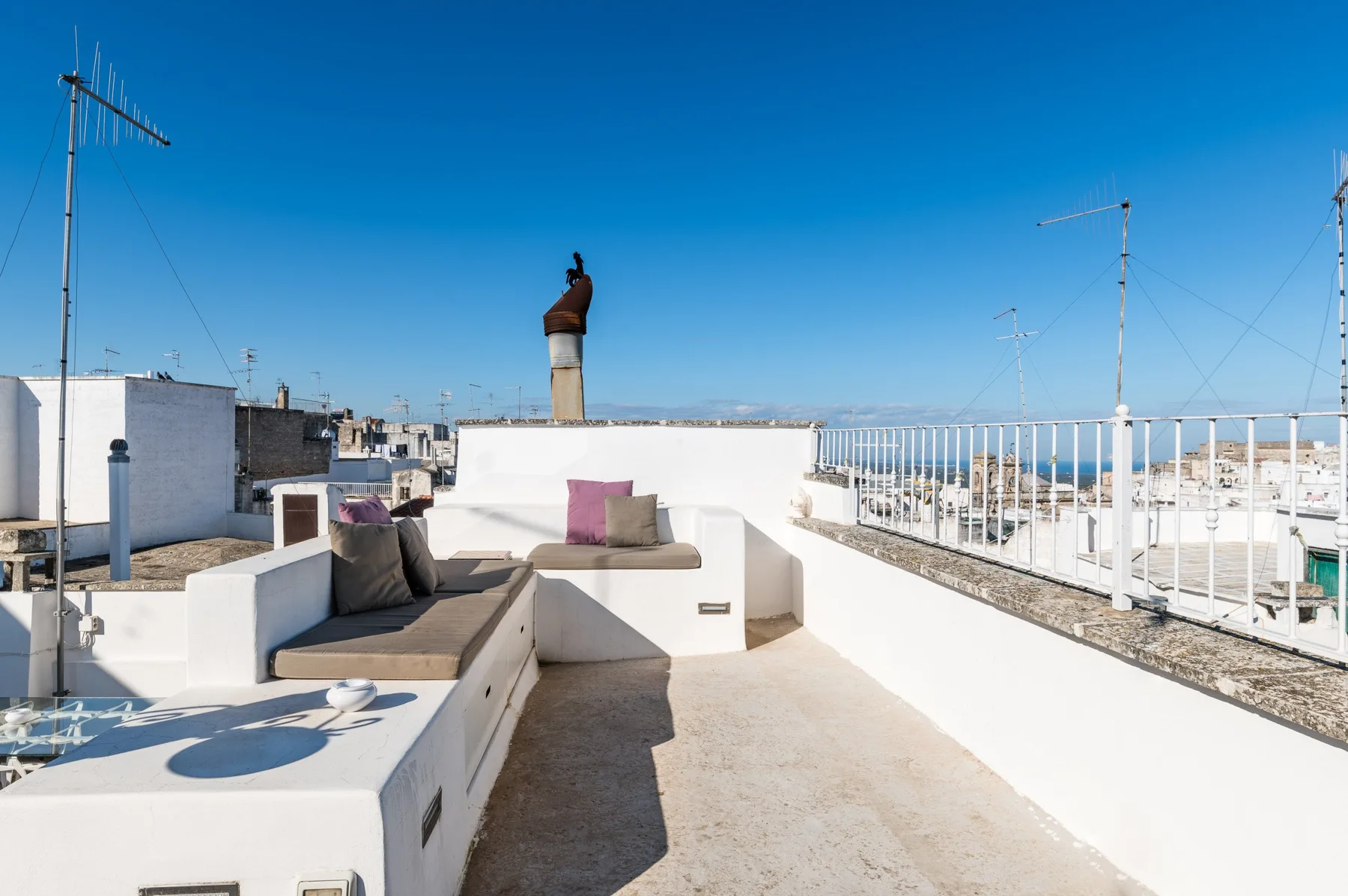 A rooftop terrace with built-in seating and a clear blue sky.