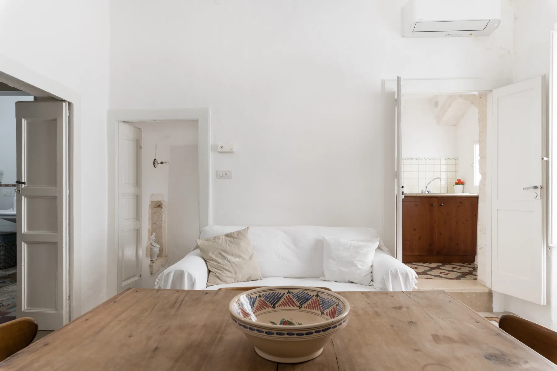 A bright living area with white seating and a wooden table.