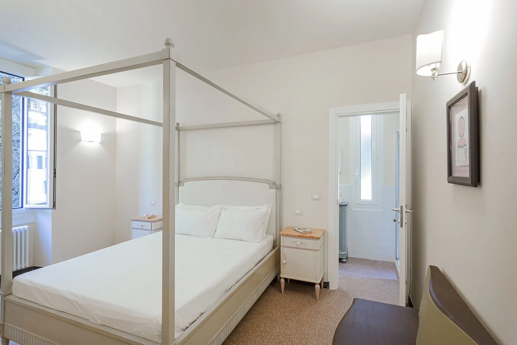 A bedroom with a bed, bedside table, and an open doorway to another room.
