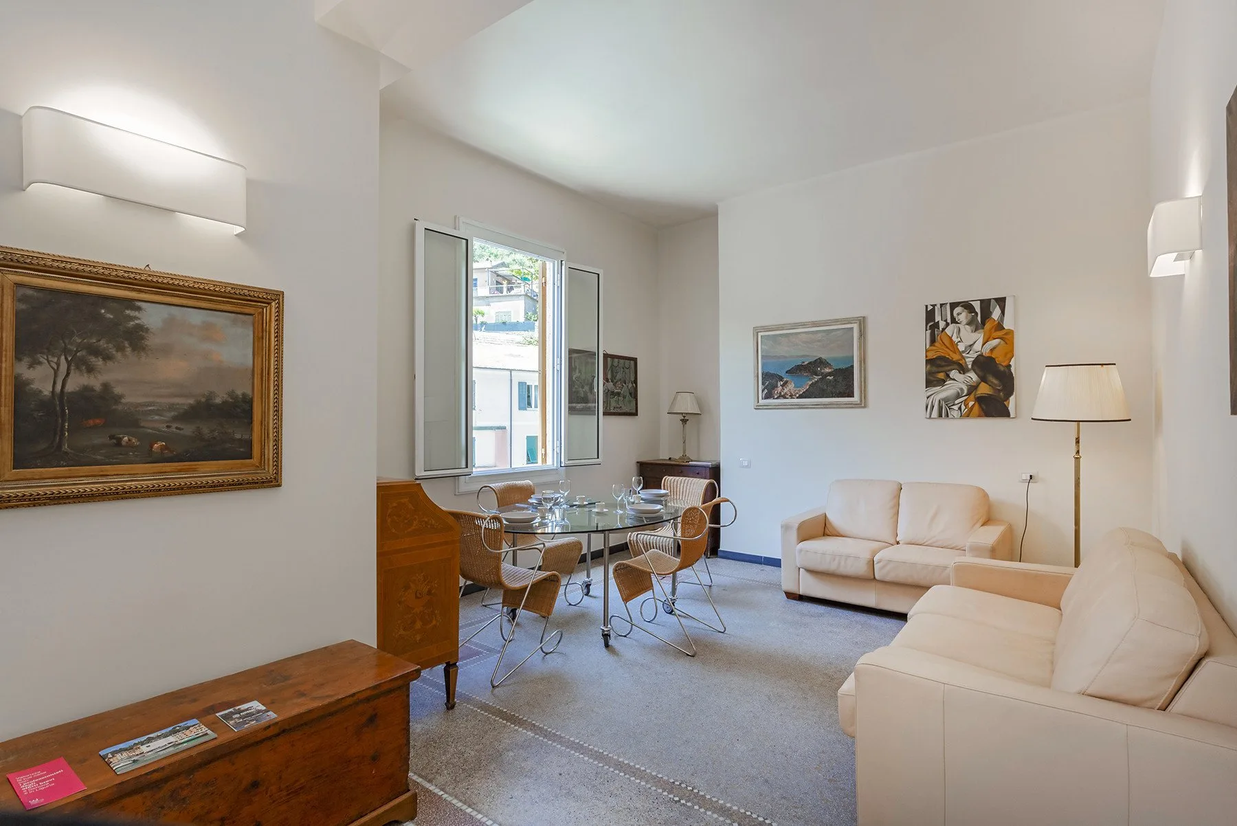 Una sala luminosa con asientos, una mesa de comedor de vidrio y obras de arte en las paredes.