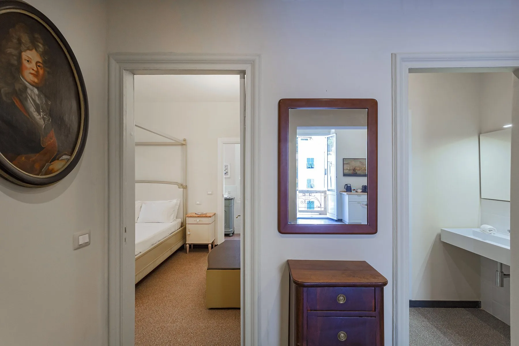Un dormitorio y un baño se abren a un pasillo con un espejo en la pared.