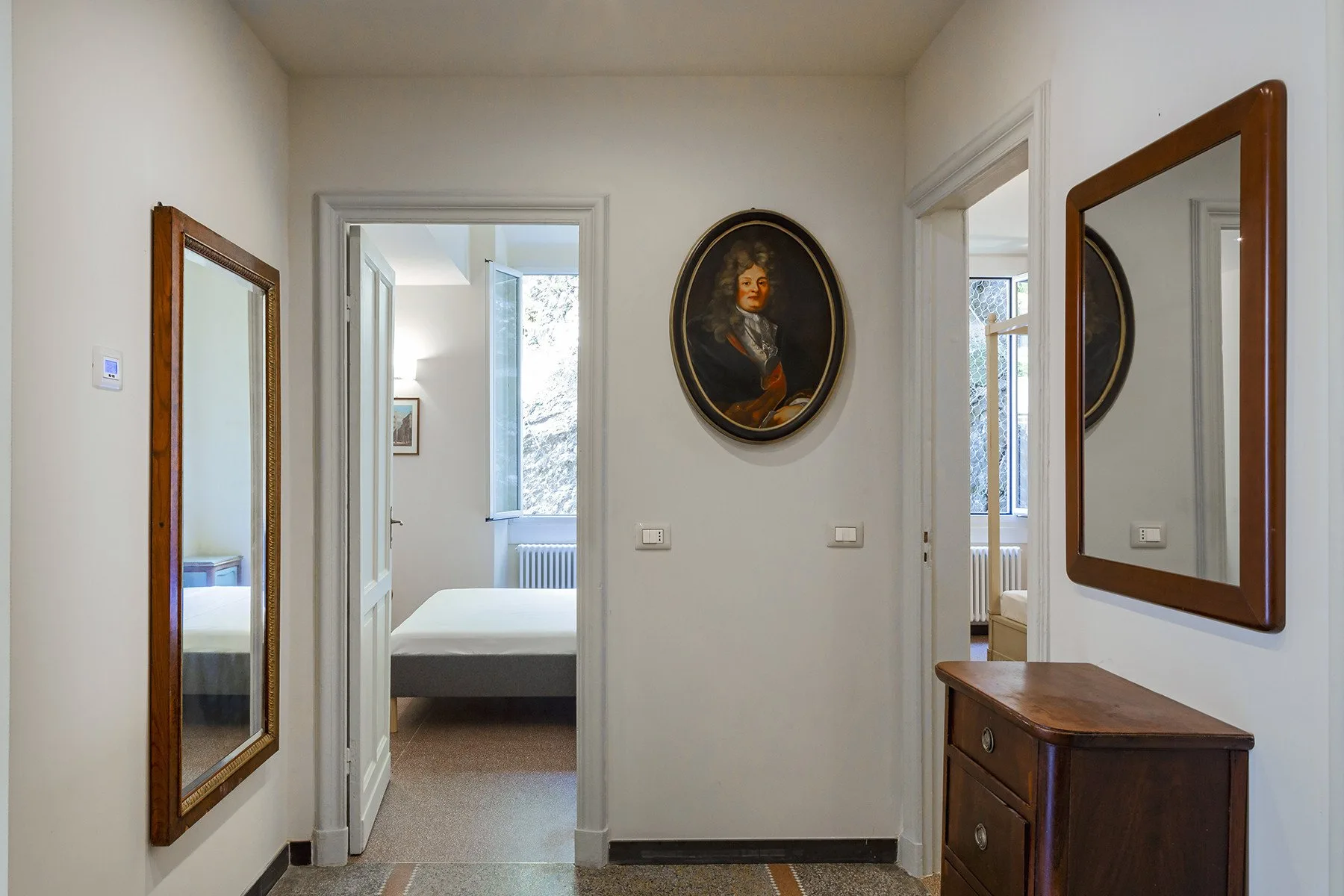 A hallway with framed artwork and open doorways leading to adjoining rooms.