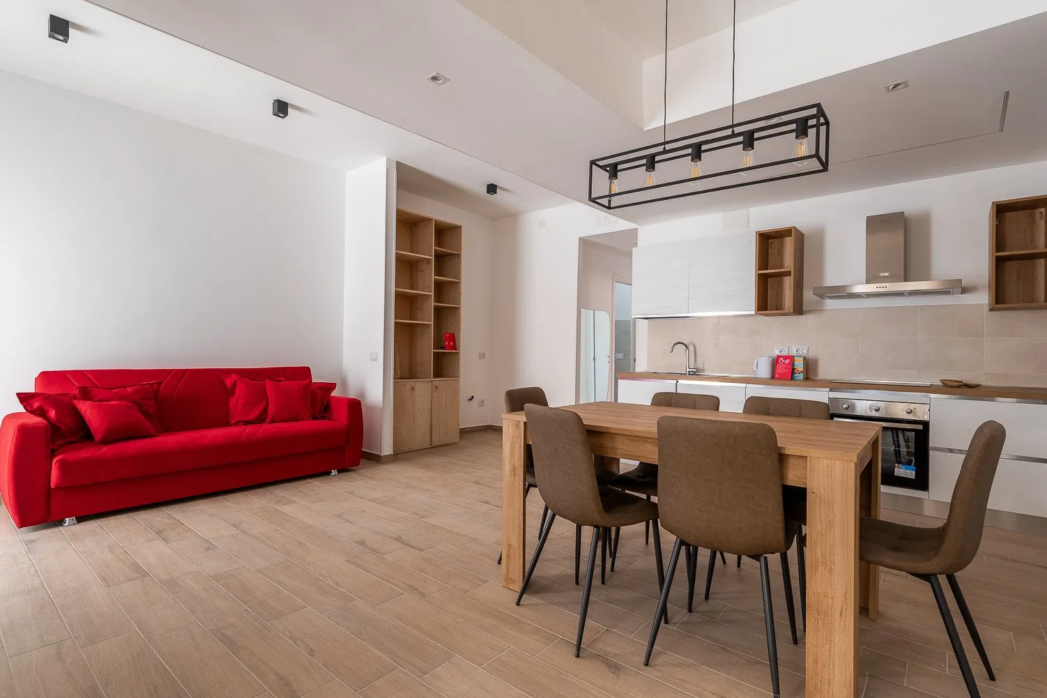 Una sala de estar y comedor con un sofá rojo y una mesa de comedor de madera.