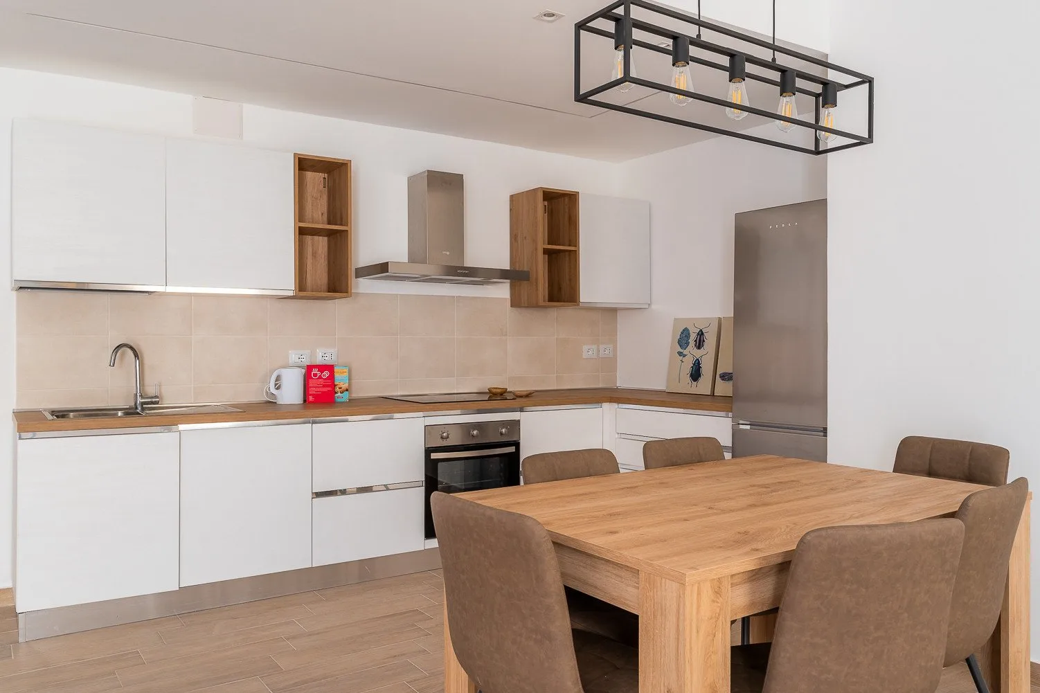 Una cocina moderna y comedor con gabinetes blancos y una mesa de madera.