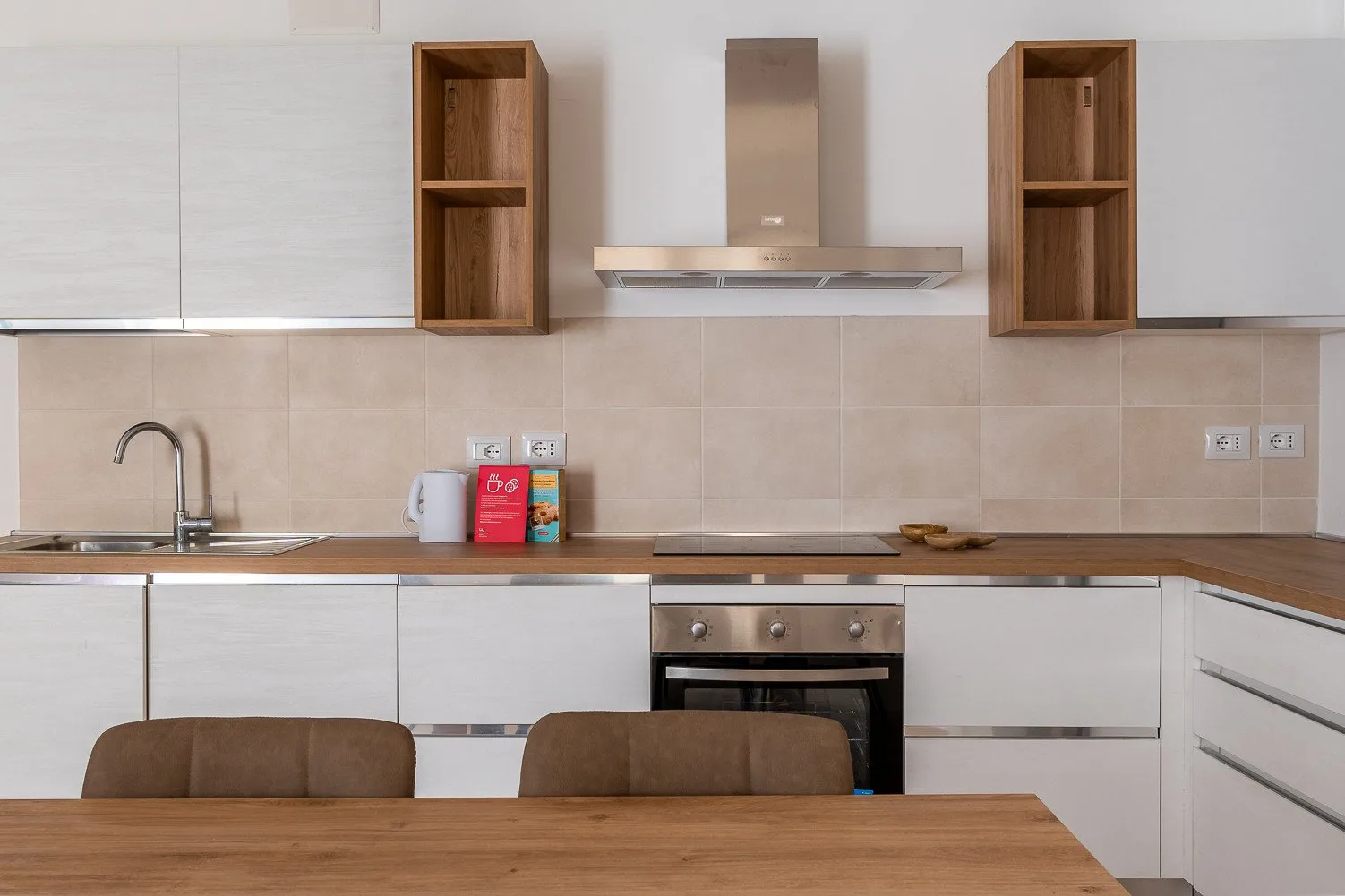 Una cocina moderna con encimera, horno y una mesa de madera en primer plano.