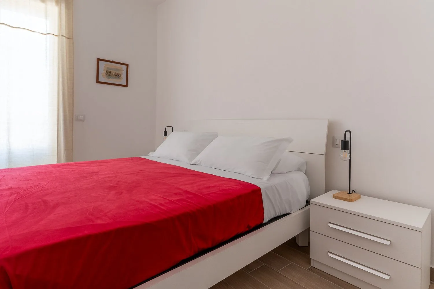 Un dormitorio con una cama cubierta por una manta roja brillante.