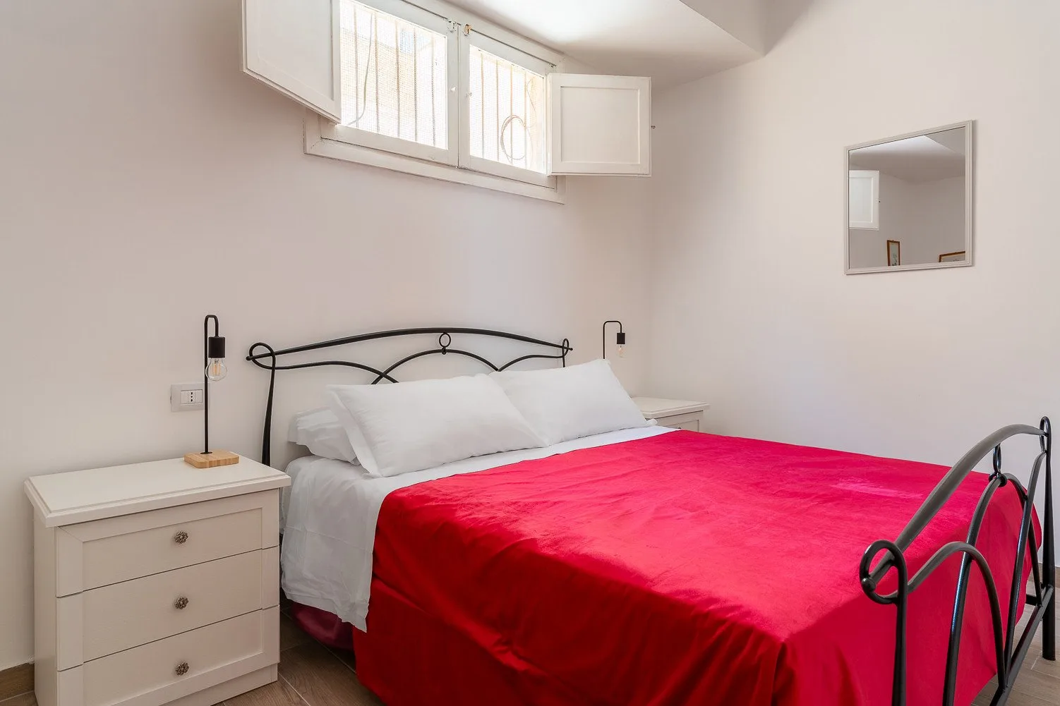 Un dormitorio con una cama cubierta por una colcha de color rojo intenso.