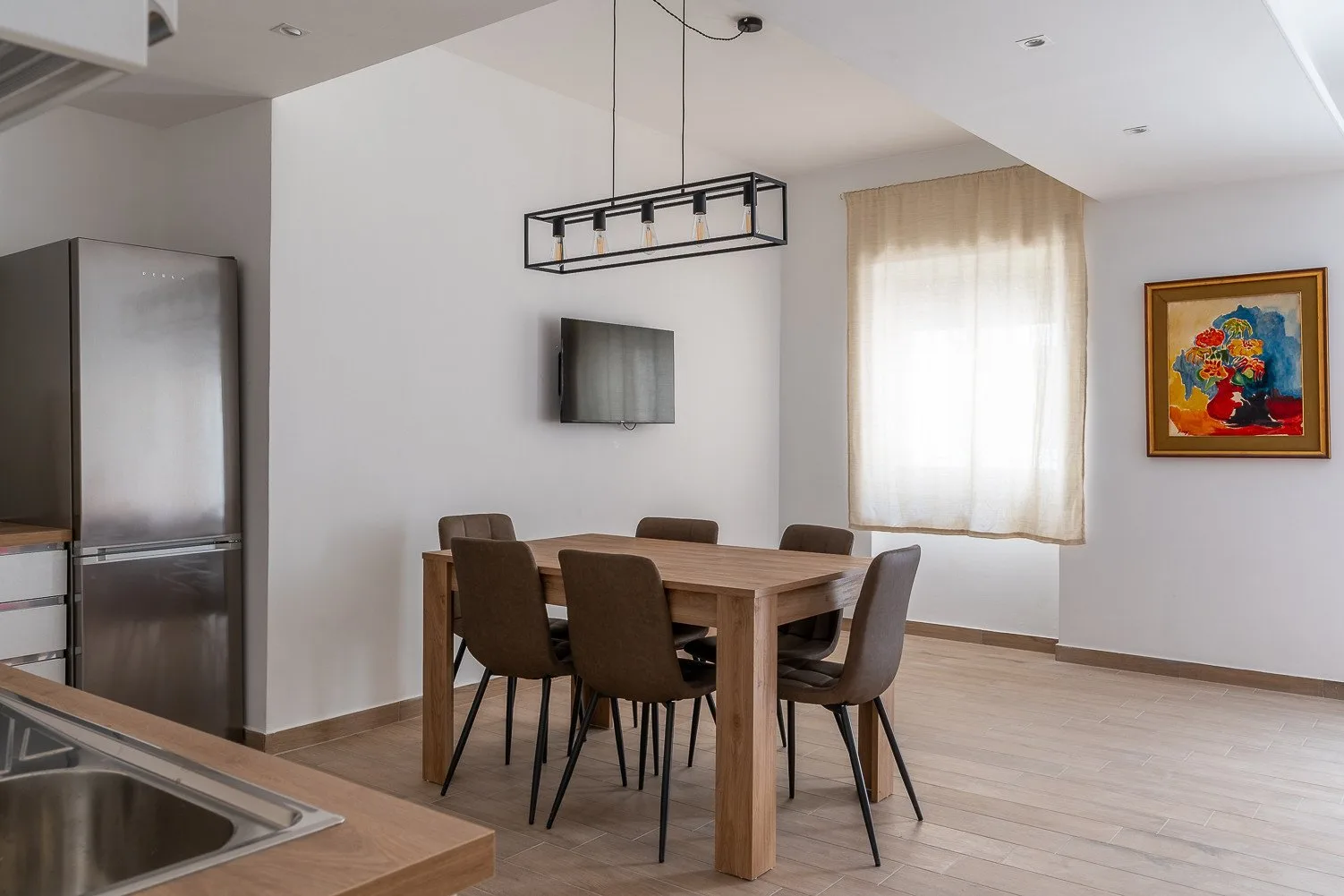 Un comedor con una mesa de madera y asientos junto a una ventana luminosa.
