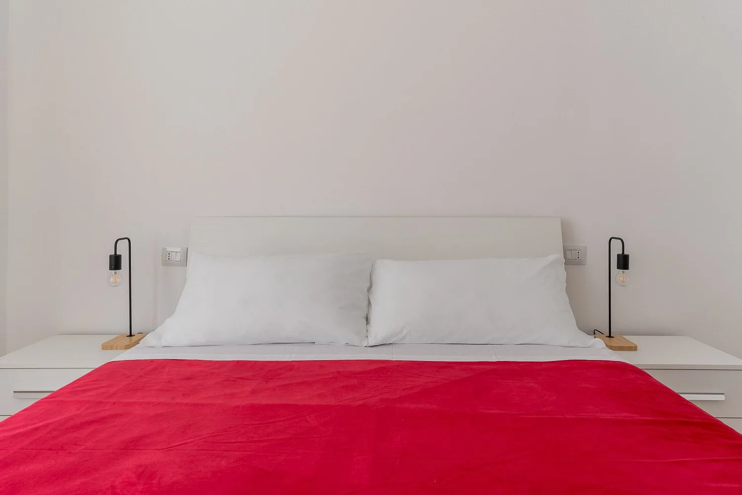 Un dormitorio con una cama cubierta por una colcha roja brillante.