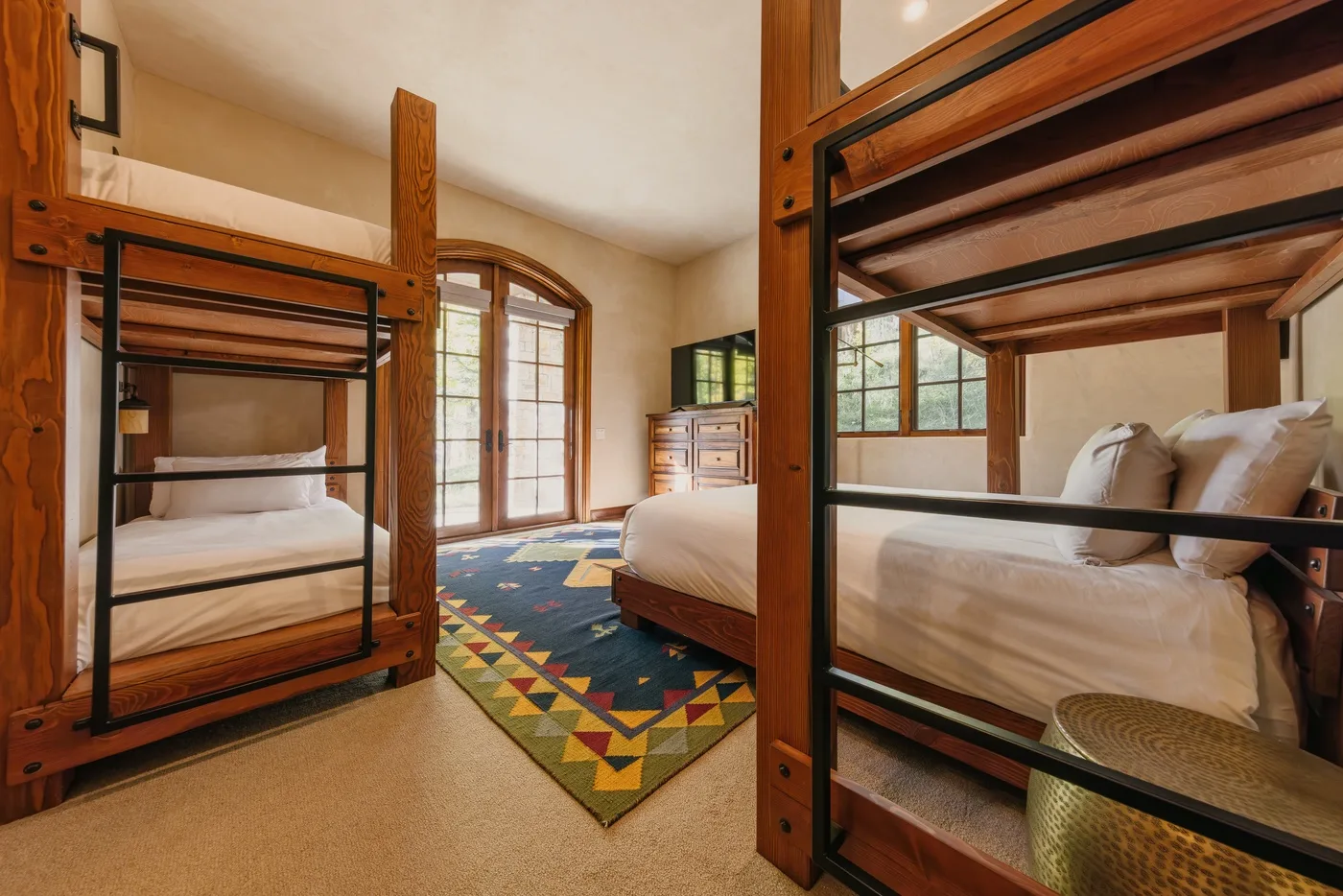 A bedroom with bunk beds, a double bed, and a colorful rug.
