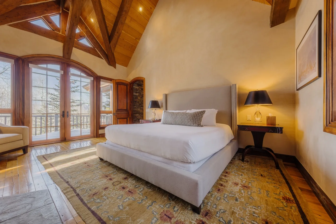 A bedroom with a large bed beneath exposed wooden ceiling beams.