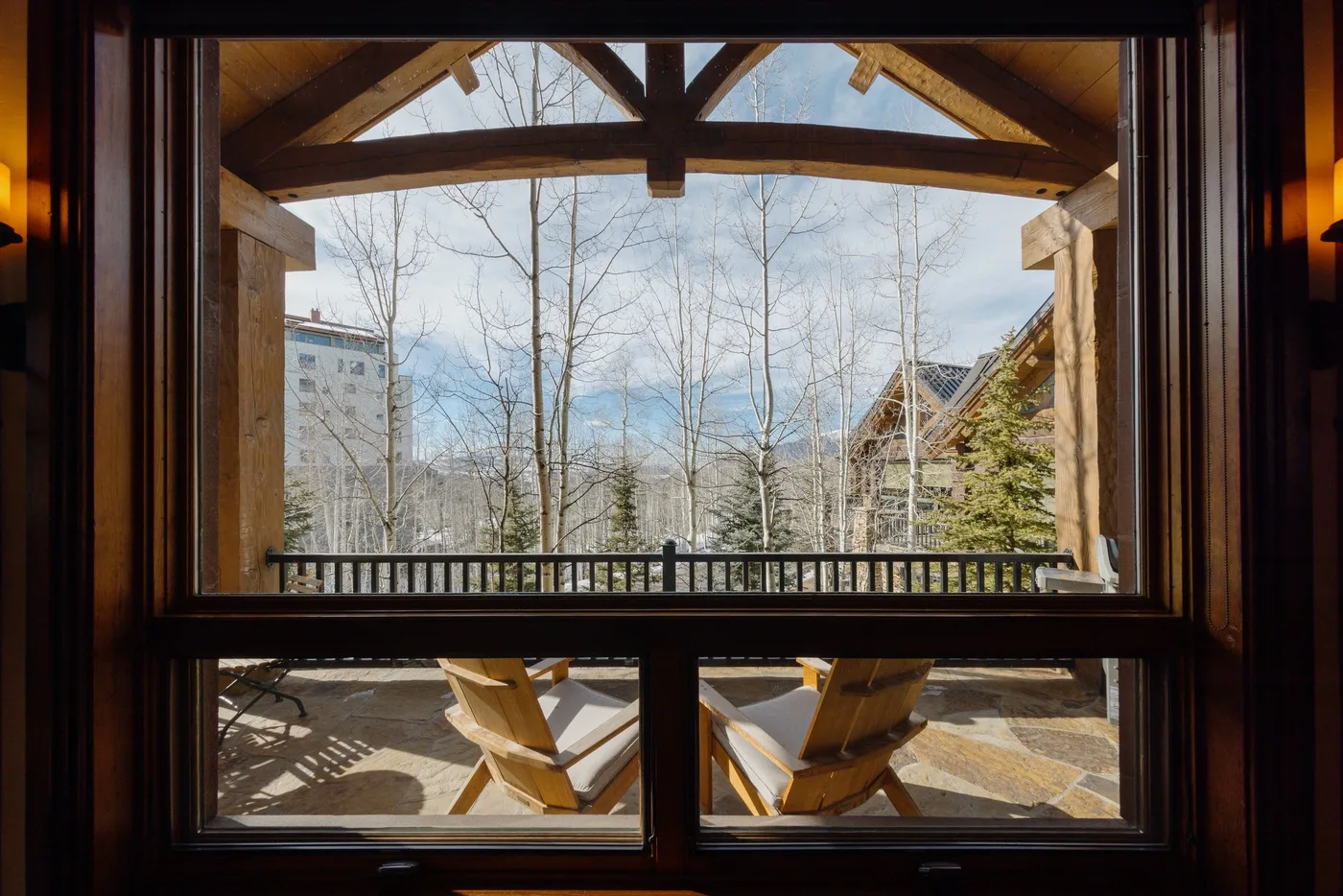 A covered patio with seating overlooks bare trees and nearby buildings.
