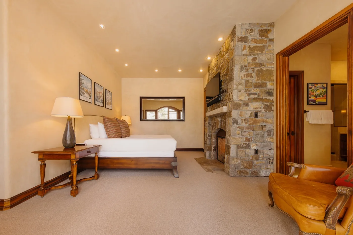 A bedroom with a bed, bedside table, and stone fireplace.