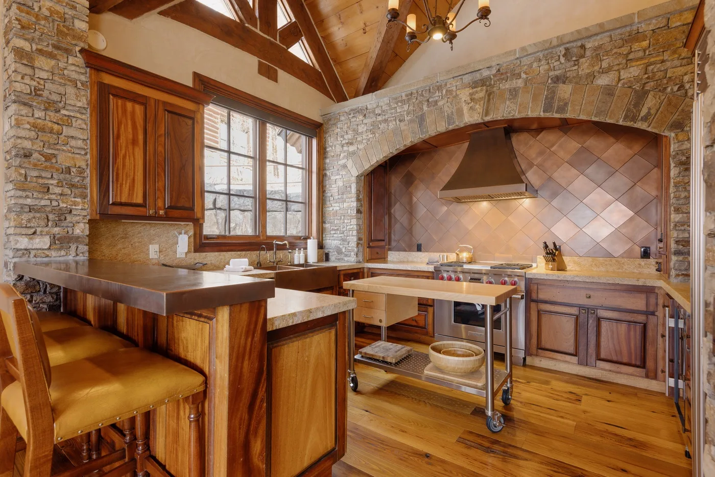 A rustic kitchen with wooden counters and a large stone arch over the cooking area.