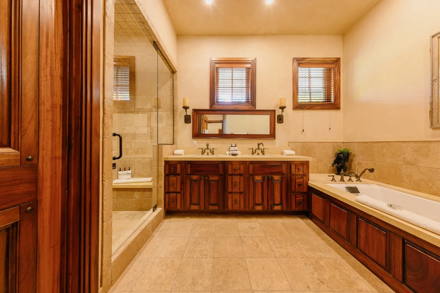 A spacious bathroom with a double vanity, glass shower, and built-in bathtub.