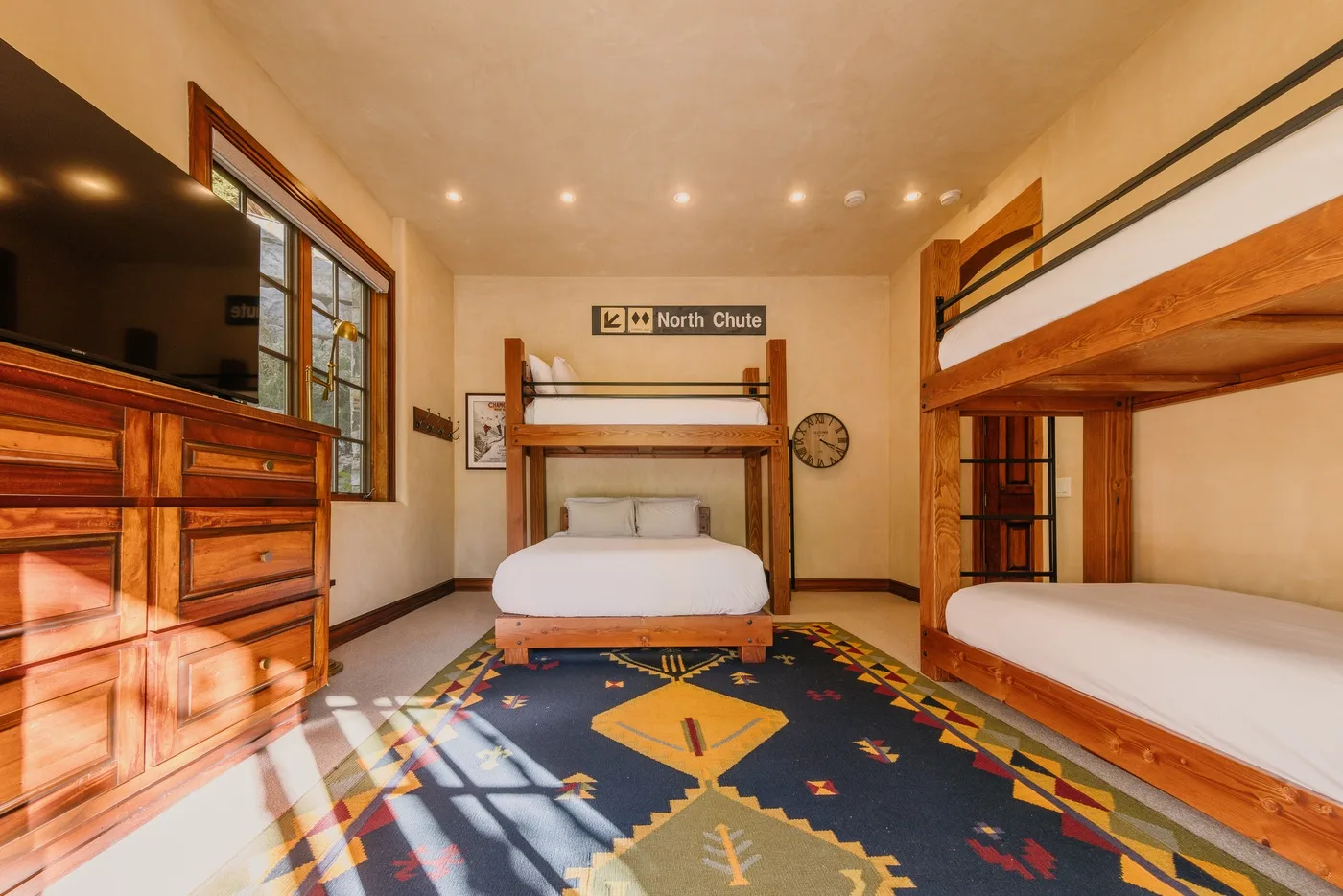 A bedroom with wooden bunk beds and a patterned rug.