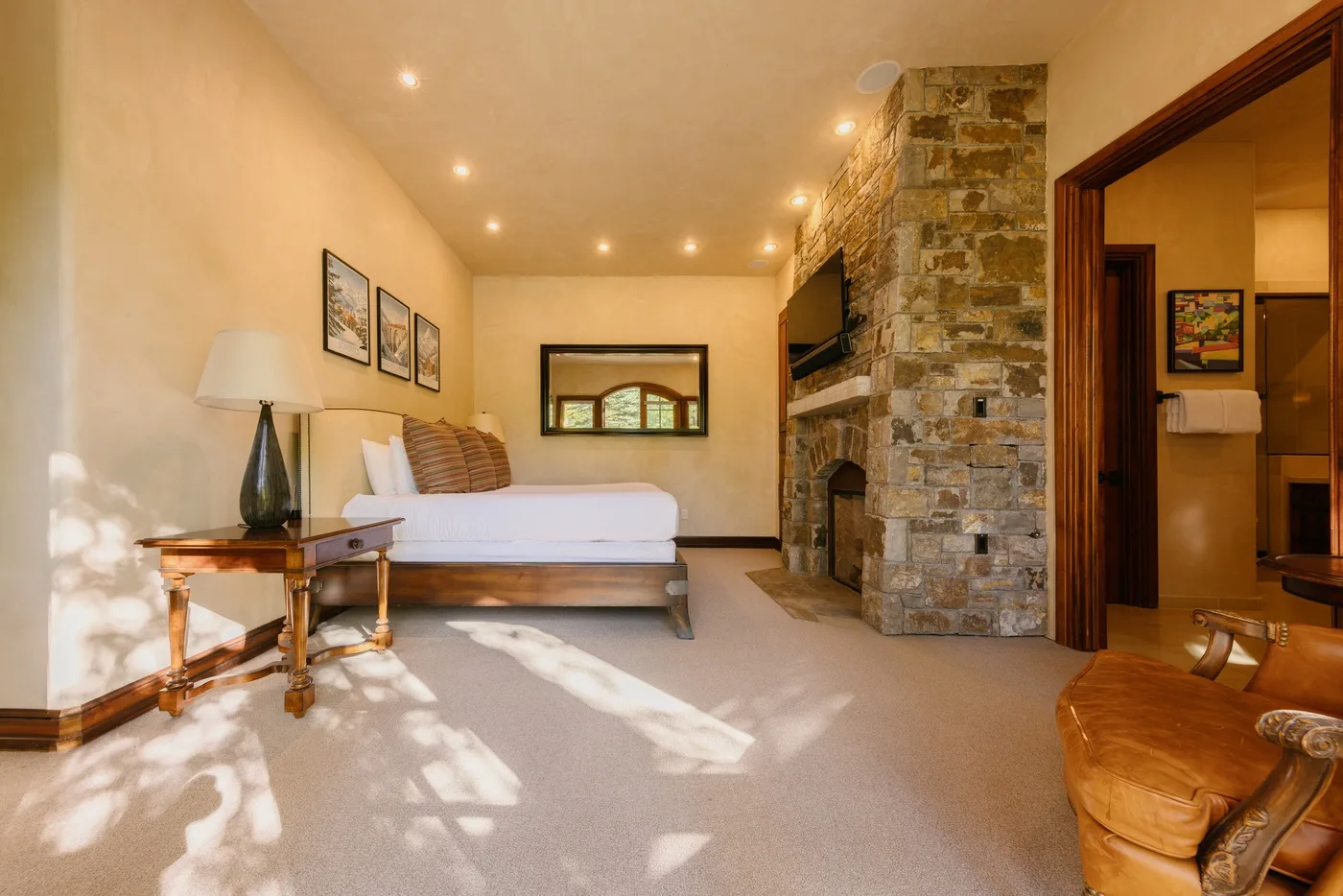 A bedroom with a bed, a stone fireplace, and a small seating area.
