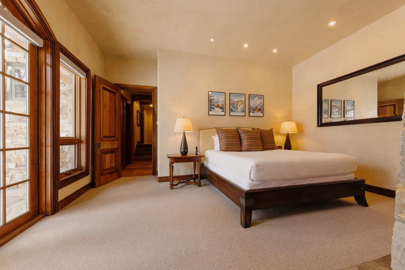 A bedroom with a large bed, bedside tables, and tall windows.
