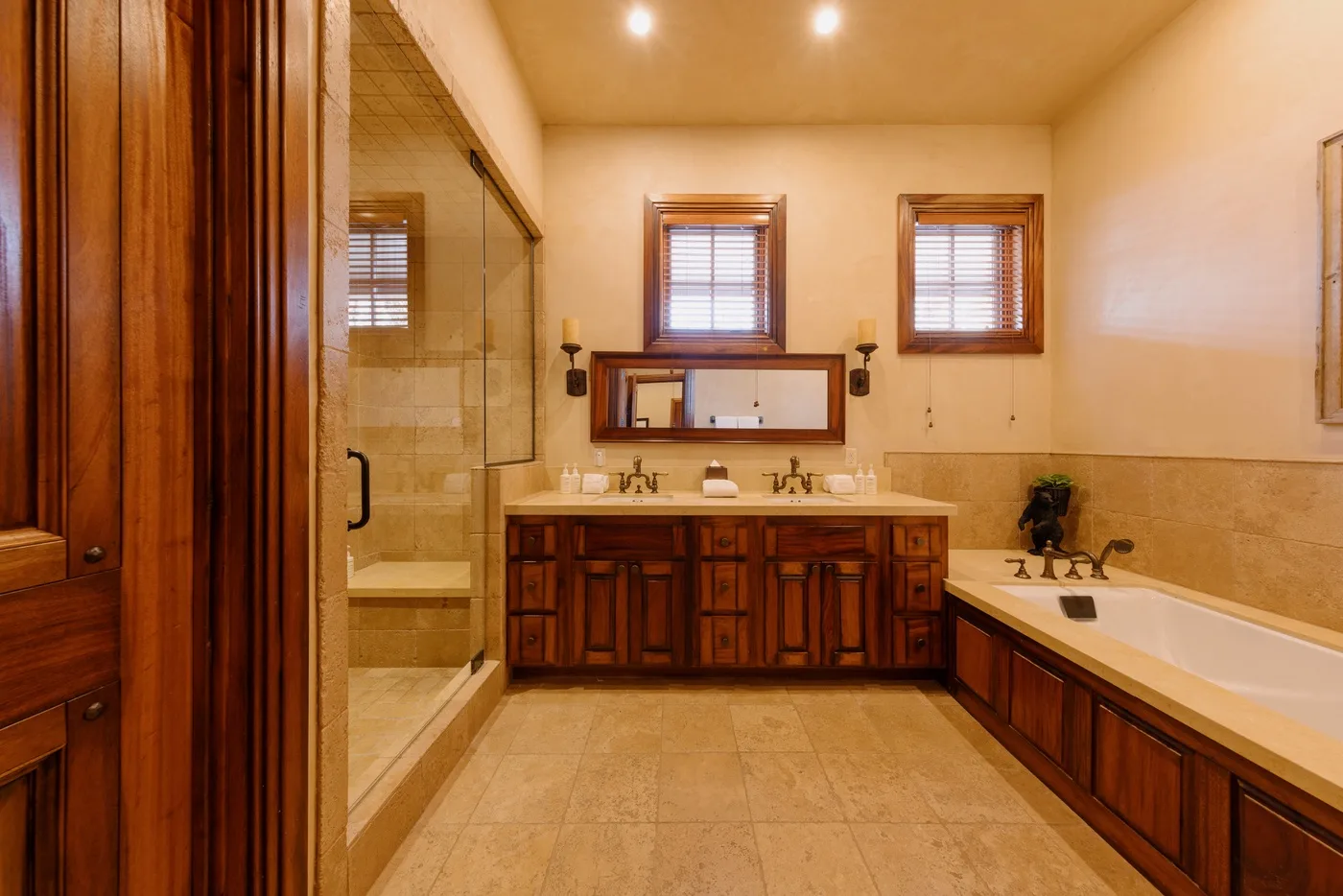 A spacious bathroom with a long vanity, windows, and a bathtub.
