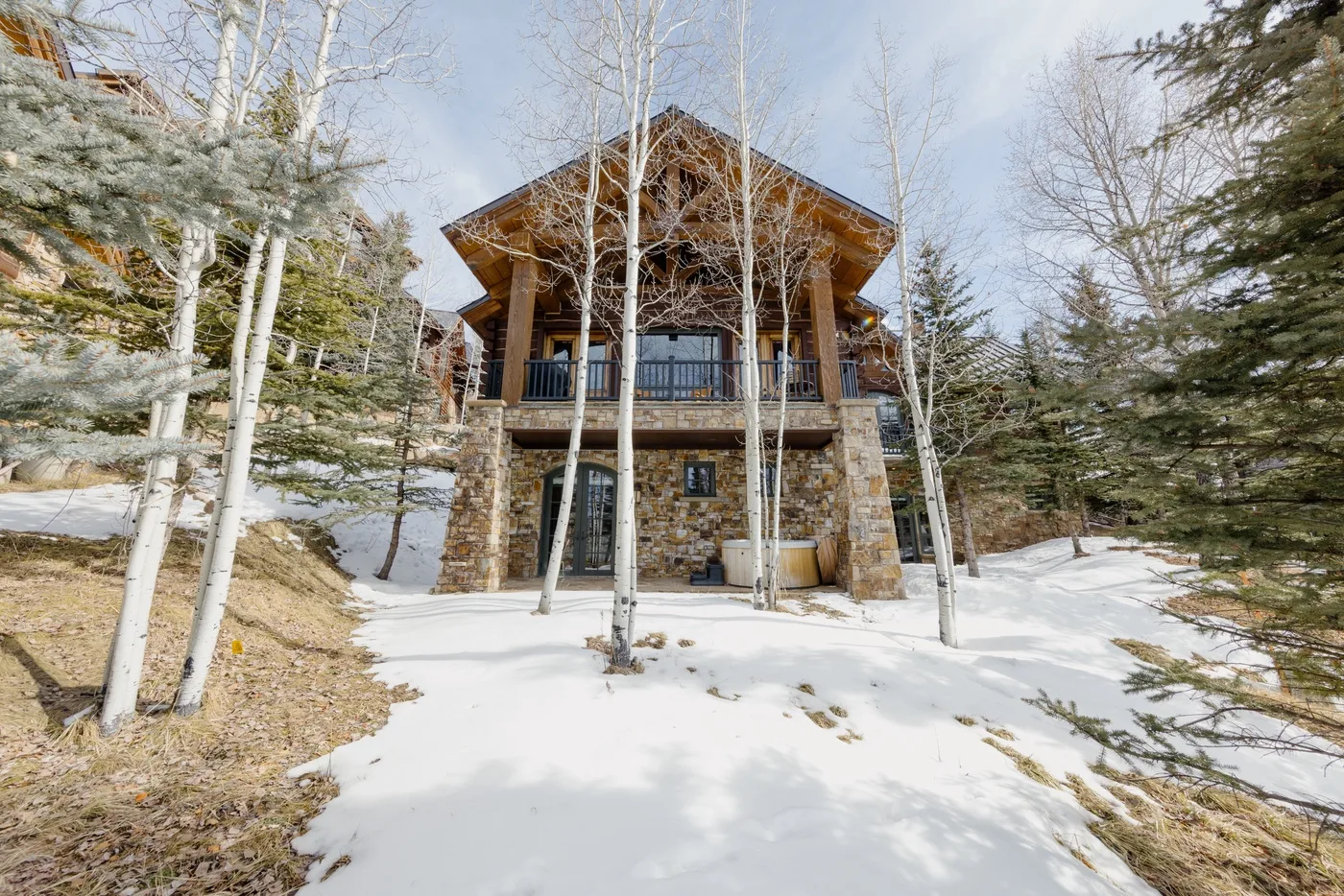A large lodge stands among trees on a snow-covered slope.