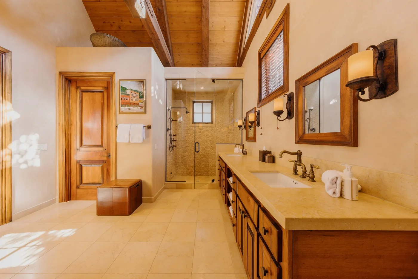 A spacious bathroom with a long vanity and a glass shower at the far end.