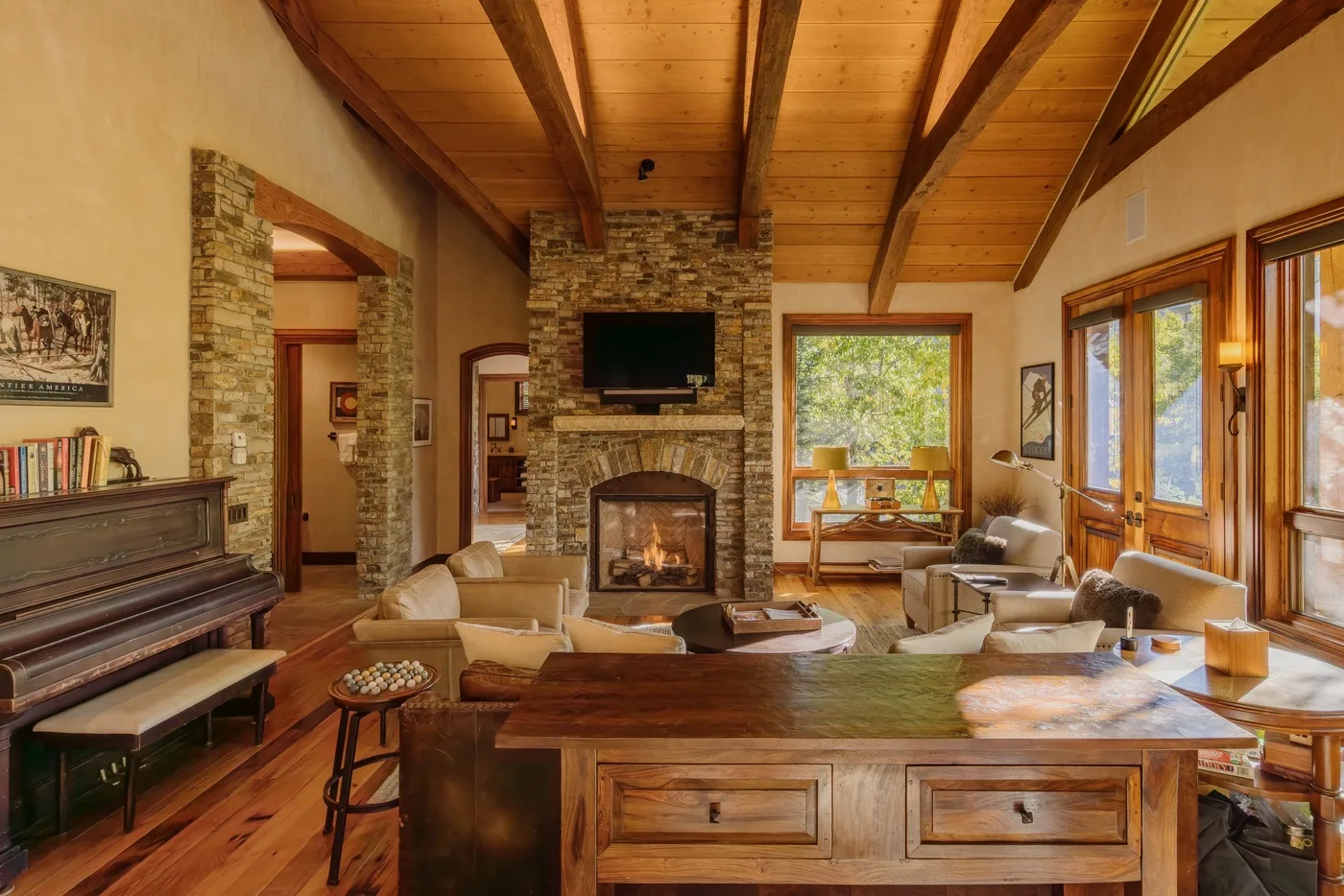 A warm living room with seating around a fireplace and large windows.