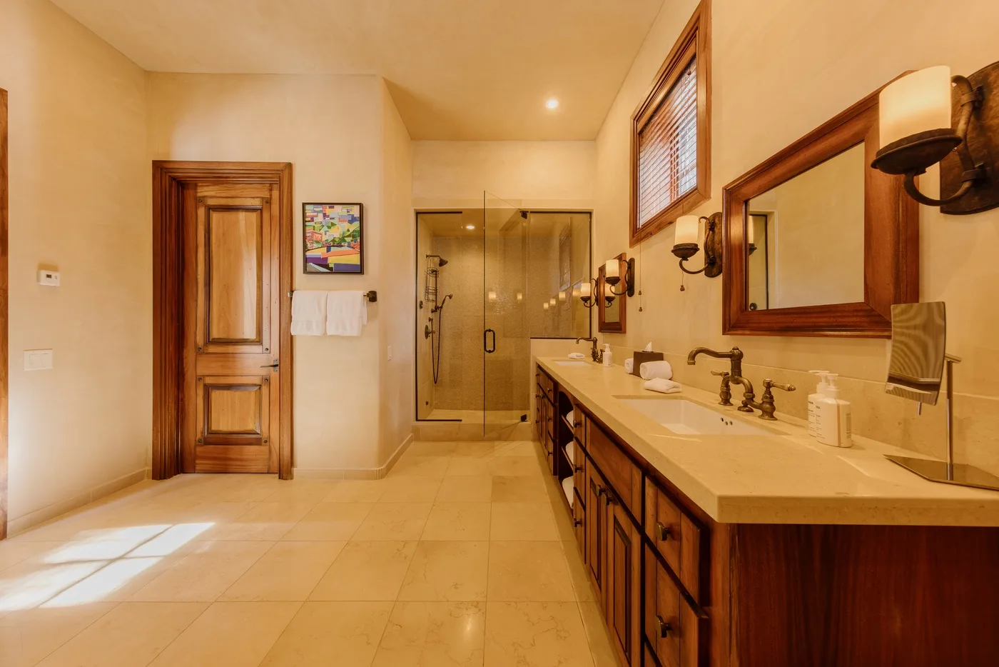 A spacious bathroom with a long vanity, wall mirrors, and a glass shower.