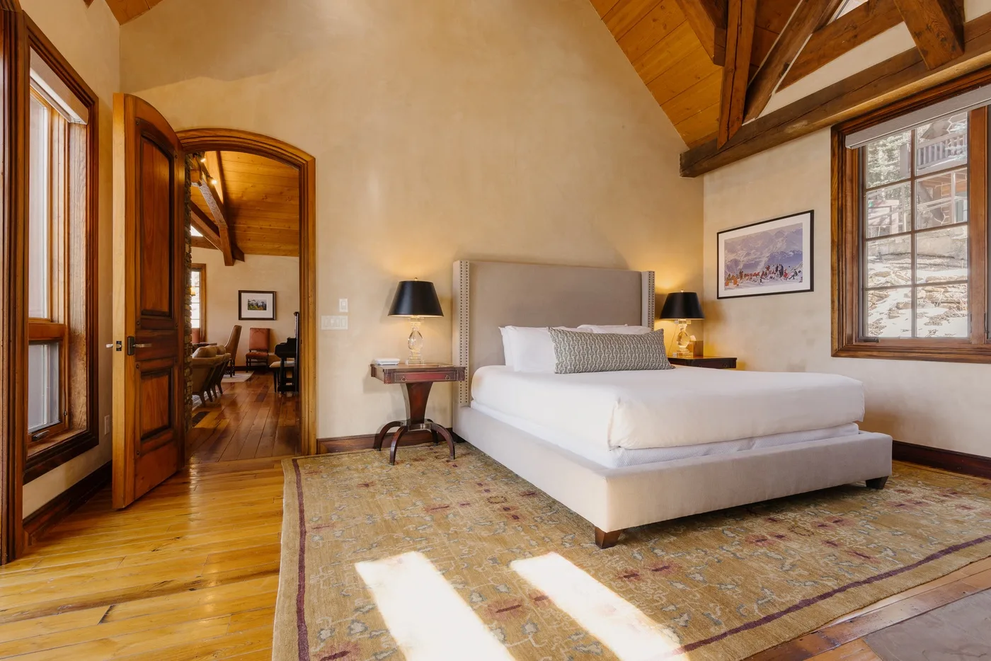 A bedroom with a bed, bedside tables, and exposed wooden ceiling beams.