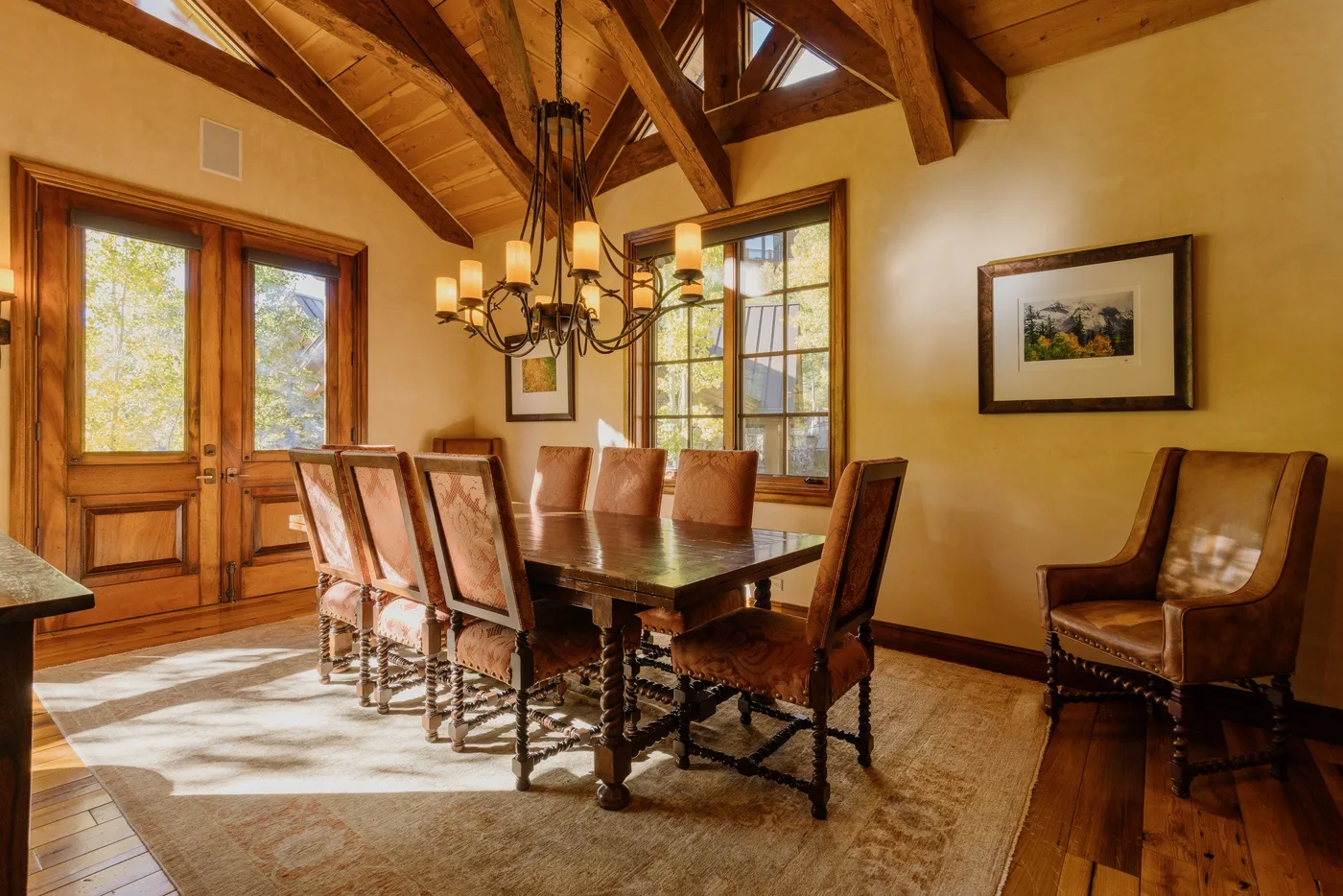 A dining room with a long wooden table beneath exposed timber ceiling beams.